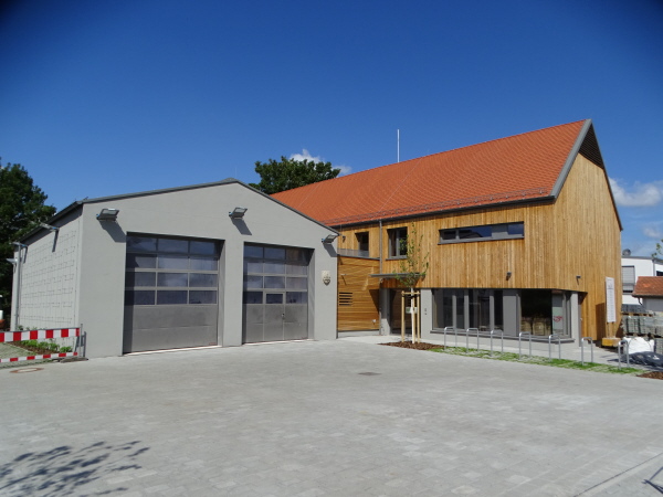 Außenansicht Bürgerhaus: Helle Holzfassade und große Feuerwehrgarage